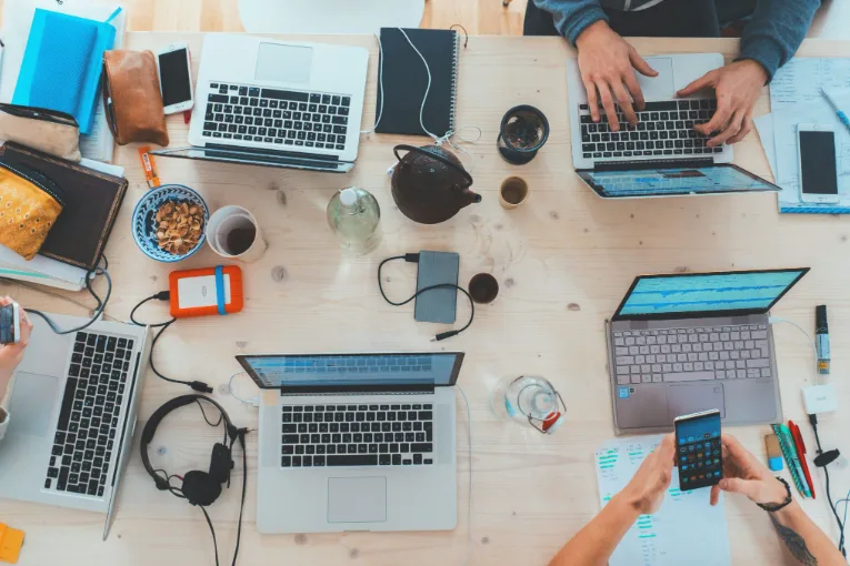 Équipe pluridisciplinaire d'une agence SEO travaillant ensemble sur plusieurs ordinateurs
